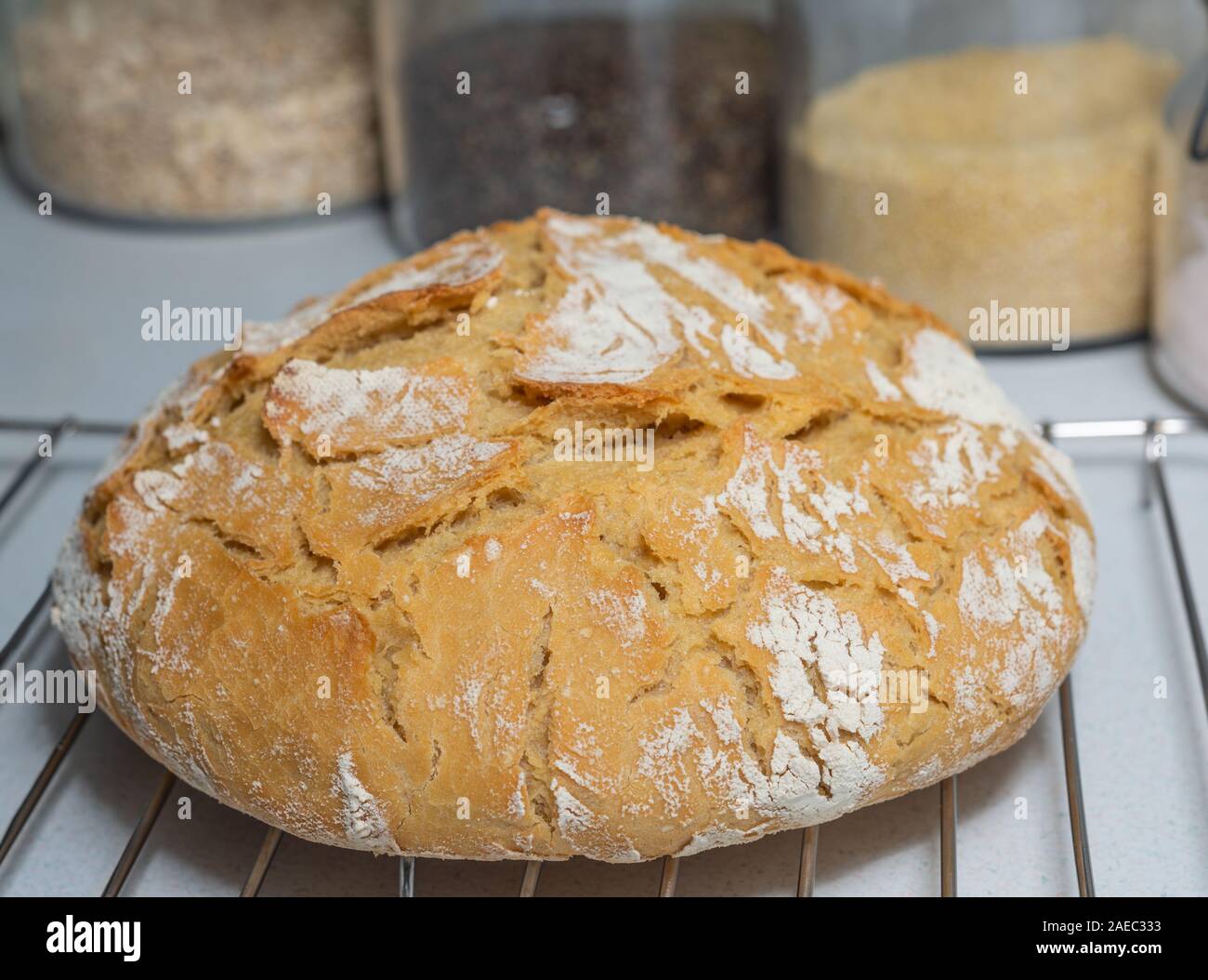 Sauerteigbrot sitzen auf einem Rack mit Gläsern im Hintergrund in der Küche. Stockfoto