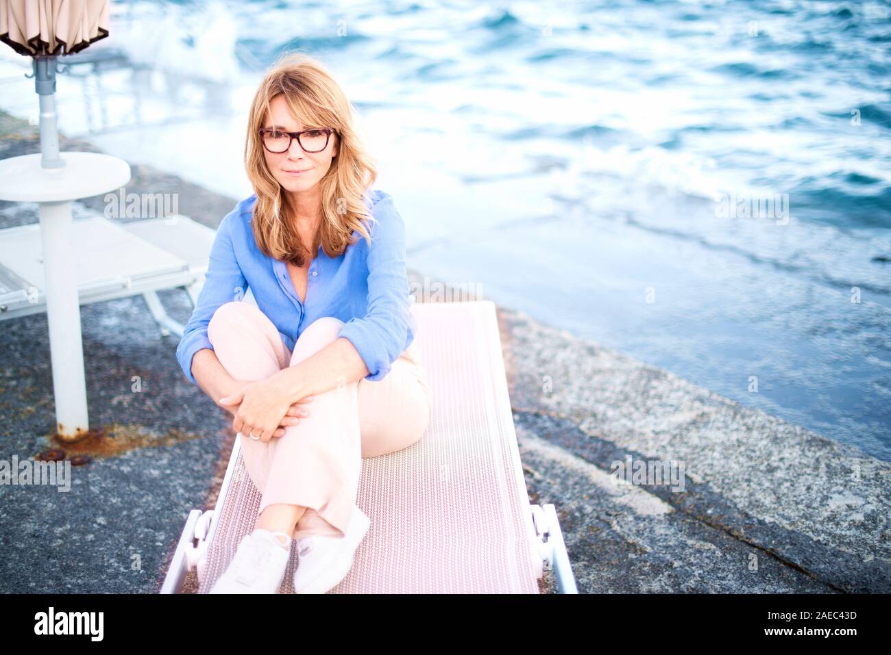 Hohen Winkel voller Länge geschossen von wunderschöne reife Frau sitzt auf der Liege und Träumen. Stockfoto