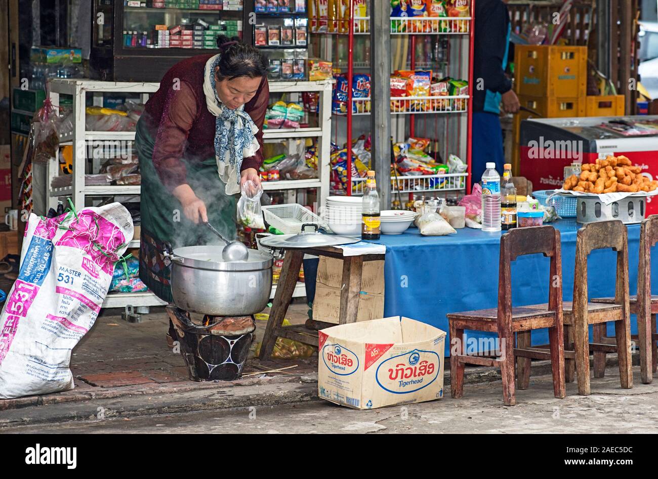 Lokale Frau zieht Suppe in einen Beutel in einer kleinen Garküche, Luang Prabang, Laos Stockfoto