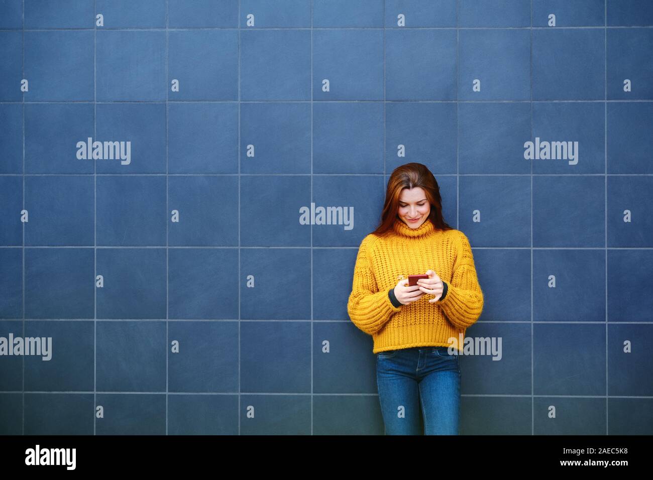 Junge rothaarige Frau Sms mit Telefon im Freien Stockfoto
