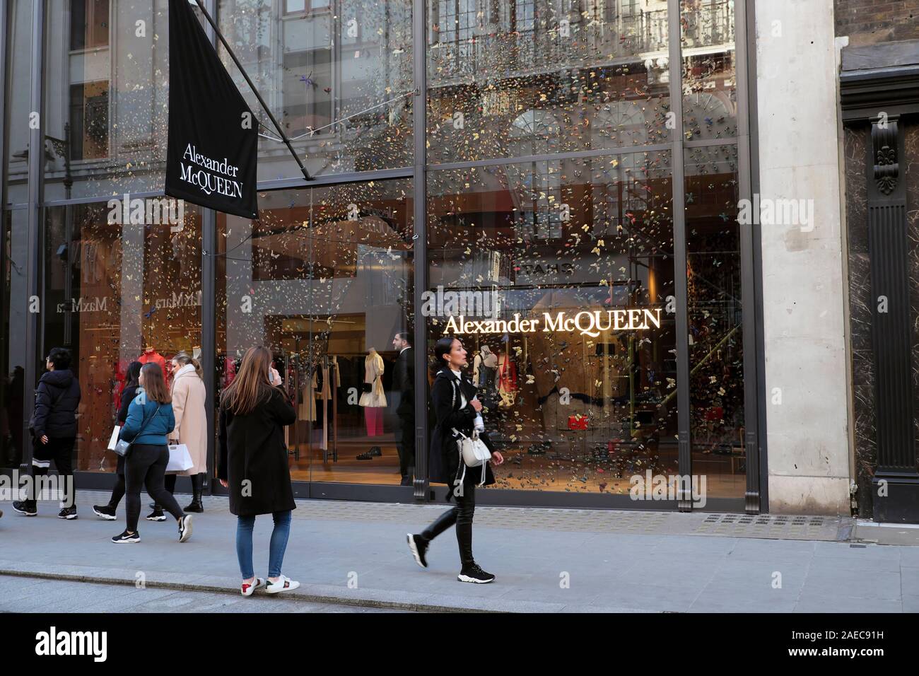 Menschen zu Fuß hinter Alexander McQueen store Exterieur Weihnachten auf Old Bond Street in Mayfair, London W1 England UK KATHY DEWITT Stockfoto
