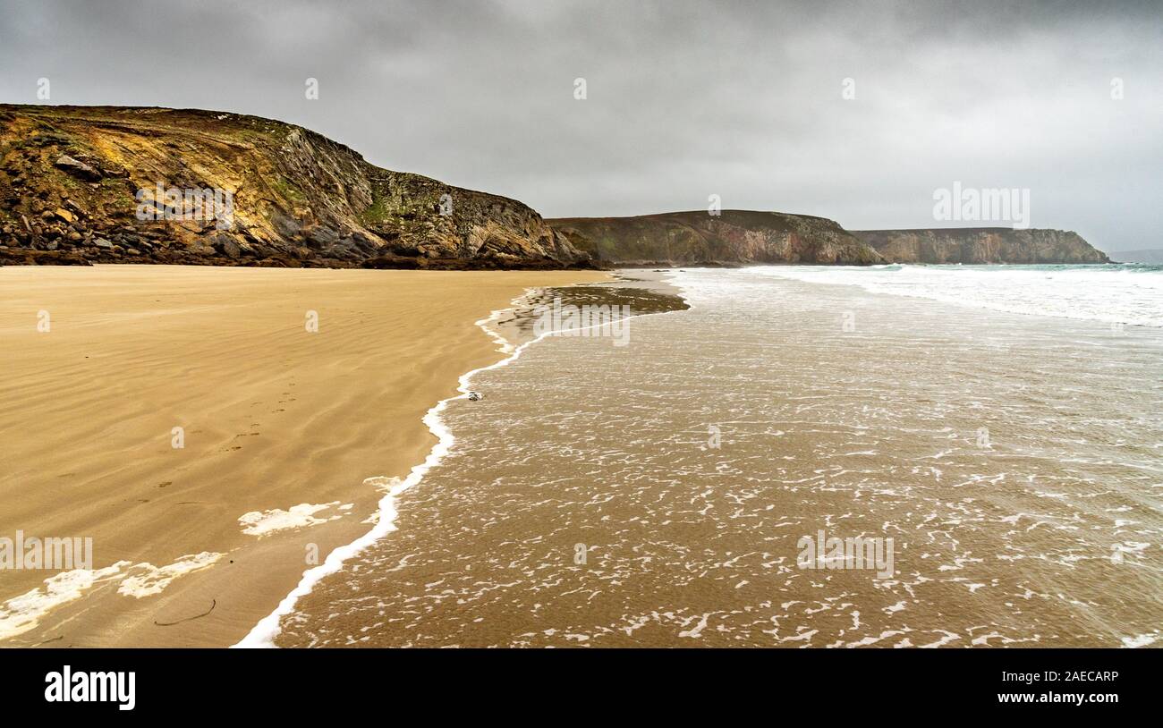 Sandstrand im Winter in der Bretagne. Die Wellen des Ozeans kommen auf den einsamen Strand unter einem grauen Himmel beladen mit Regen zu sterben Stockfoto