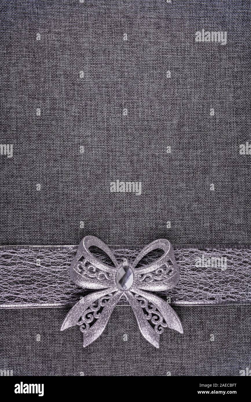 Glänzendes band Silver glitter Bug auf Silber Farbband und auf Grau texturierte Sackleinen. Bogen und Band sind unten auf dem Bild. Verti Stockfoto