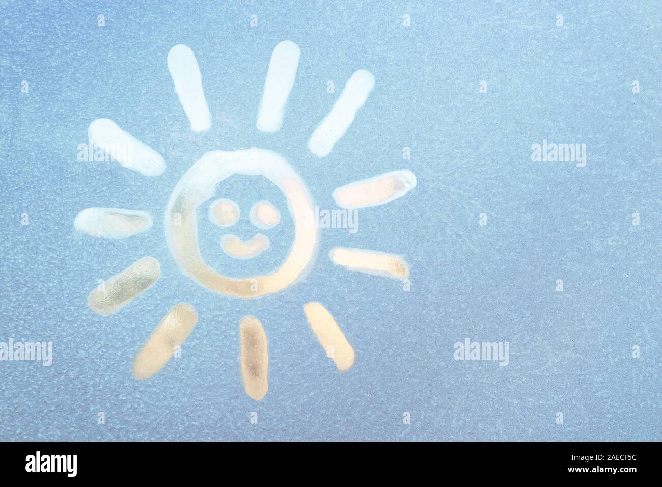 Lächelnde Sonne auf einem gefrorenen Fenster gemalt, Winter Spaß, Jahreszeit und hoffe Konzept. Stockfoto