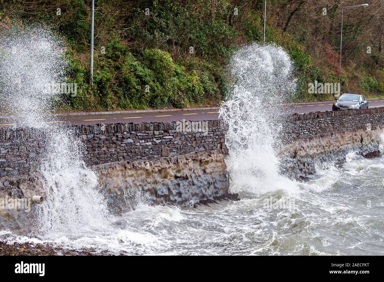 Bantry, West Cork, Irland. Dezember 2019. Sturm Atiyah traf West Cork an diesem Nachmittag mit Winden bis zu 100kmh. Ein Auto fährt entlang der N71 nach Bantry, während große Wellen die Meeresmauer durchbrechen. Quelle: AG News/Alamy Live News Stockfoto