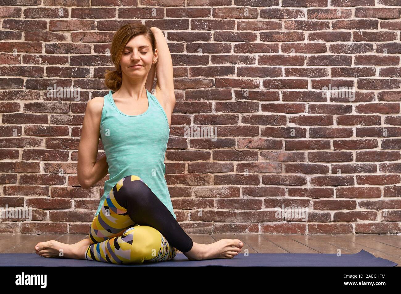 Sportlich attraktive junge Frau Yoga Übung, Arbeiten, tragen Sportswear, volle Länge, ziegelwand Hintergrund Stockfoto