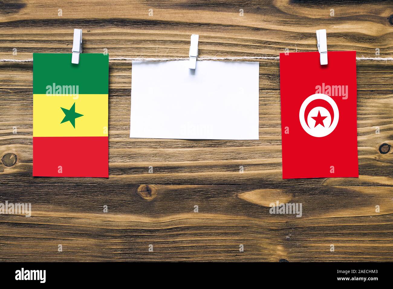 Hängenden Flaggen von Senegal und Tunesien, Seil mit wäscheklammer mit Kopie Raum befestigt auf weißem Papier auf Holz- Hintergrund. Diplomatische Beziehungen Stockfoto