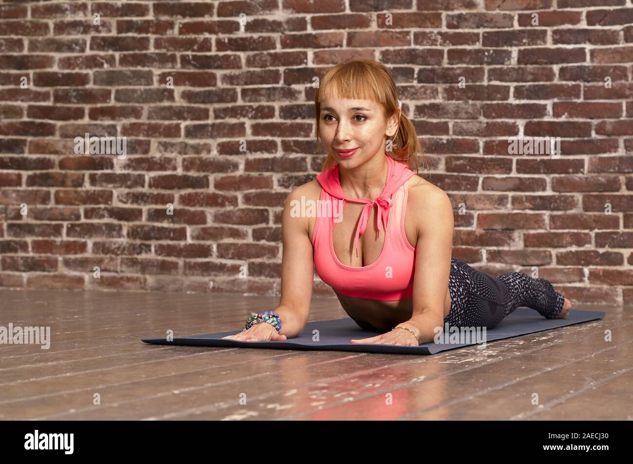 Sportlich attraktive junge Frau Yoga Übung, Arbeiten, tragen Sportswear, volle Länge, ziegelwand Hintergrund Stockfoto