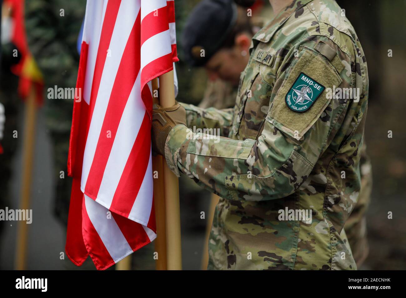 Bukarest, Rumänien - Dezember 03, 2019: US-Armee Soldat Holding eine Fahne und in MNDSE (Multinationale Division Südost) Insignia. Stockfoto