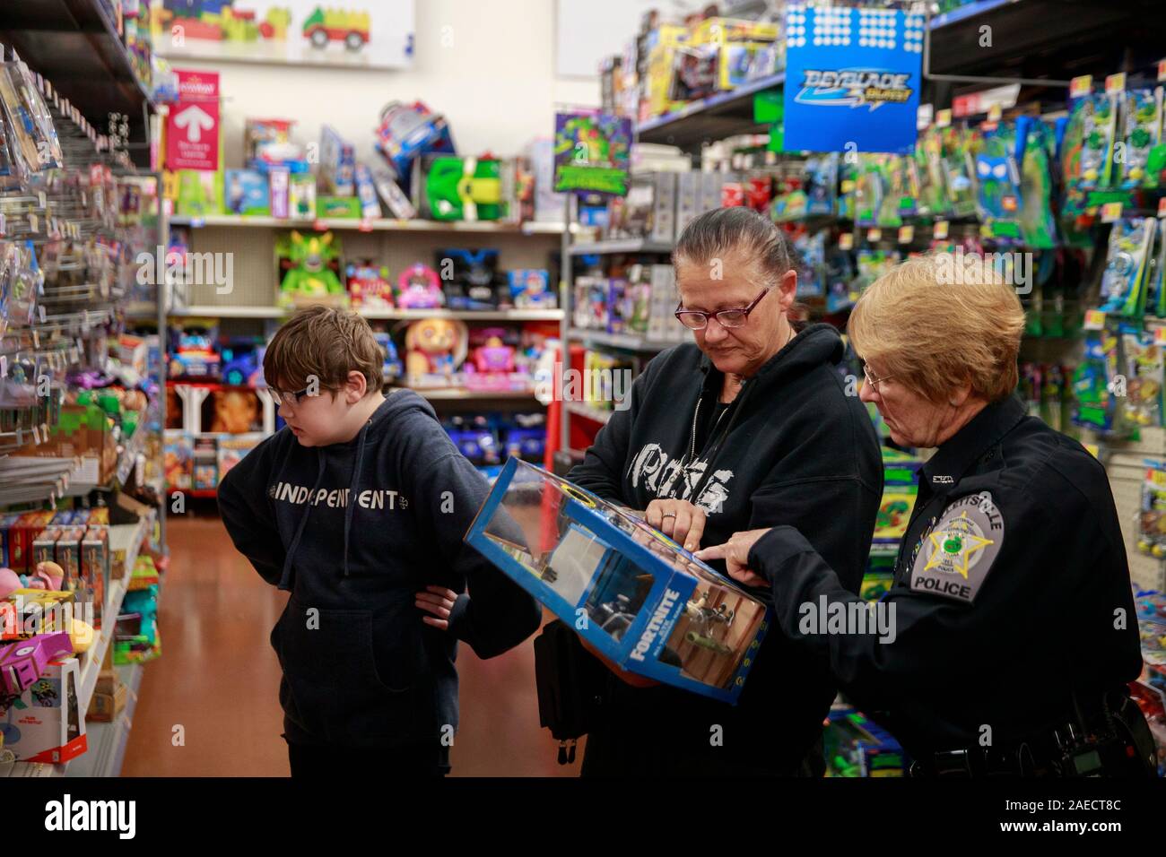 Elllettsville Polizeioffizier Gail Jones, rechts, hilft Kim Kent, das Einkaufen ist mit ihrem Enkel LeBron Kent, links, beim Geschäft mit einer Spindel, Sonntag, Dezember 8, 2019 in Bloomington, Ind. Mitglieder der Strafverfolgung von Monroe County einschließlich der Mitglieder der IUPD, Bloomington Police Department, Monroe County Sheriff's Office und Ellettsville Polizei Abteilung im Falle von der Don Owens Memorial brüderliche Auftrag der Polizei Lodge 88 teilgenommen. (Foto von Jeremy Hogan/Die Bloomingtonian) Stockfoto