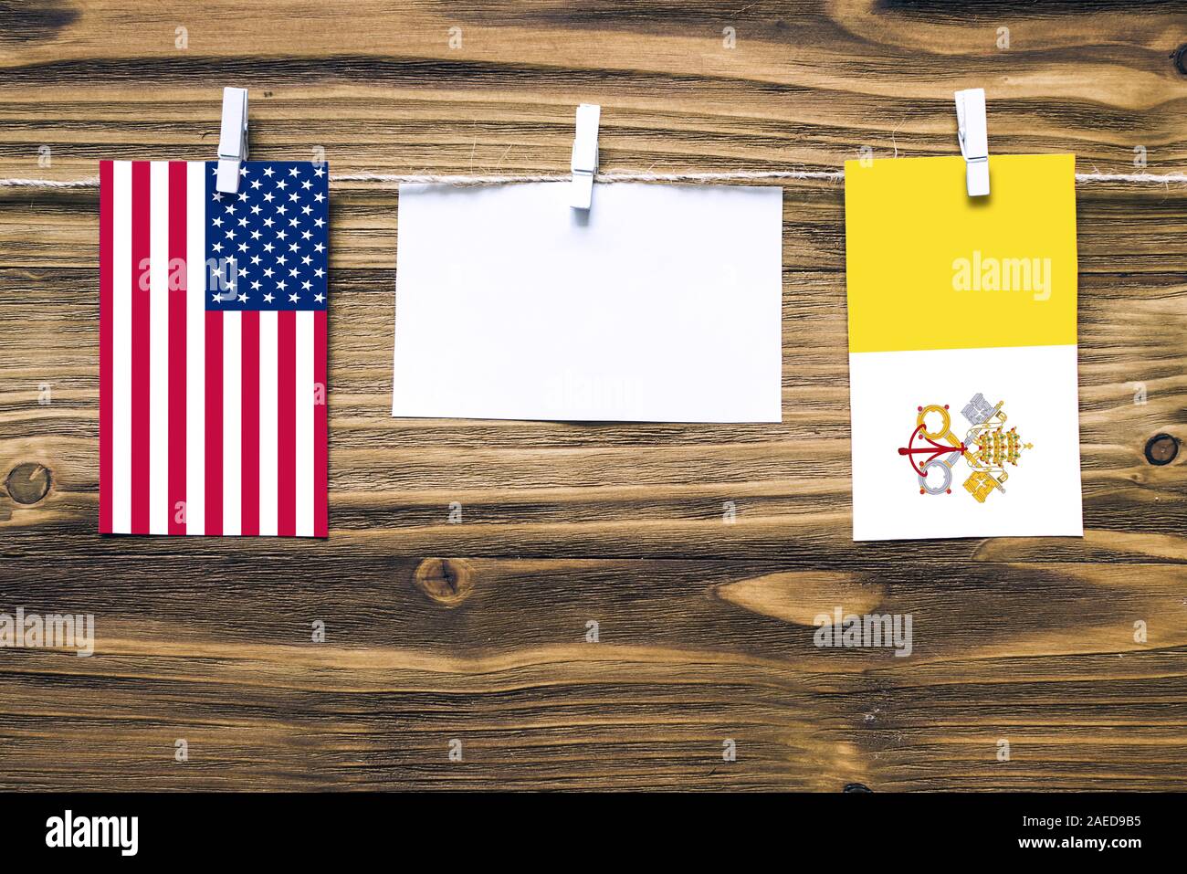 Hängenden Flaggen der Vereinigten Staaten von Amerika und Vatikanstadt zu Seil mit wäscheklammer mit Kopie Raum befestigt auf weißem Papier auf Holz- Hintergrund. Diplomatischen Stockfoto
