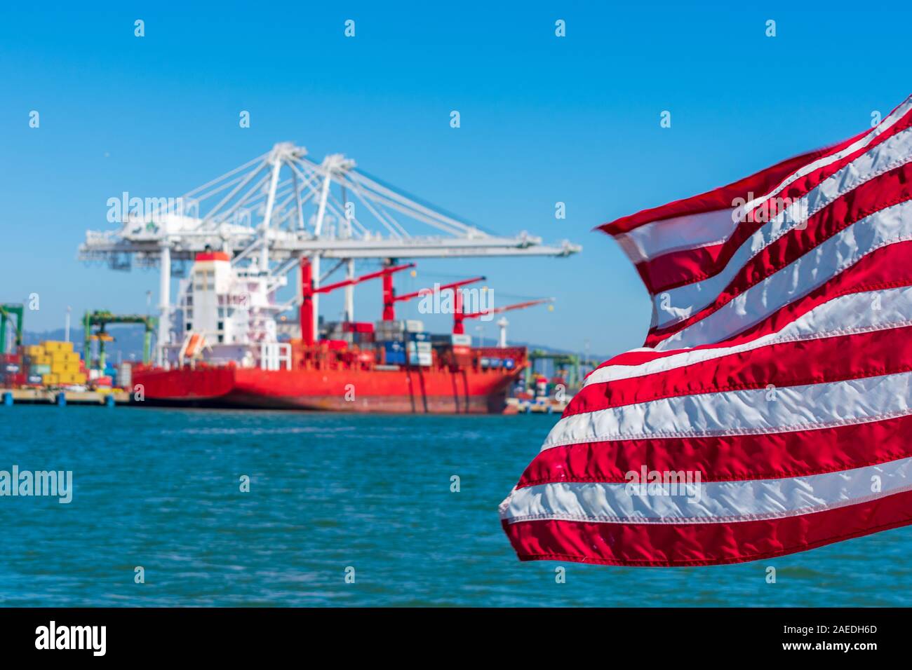 Flagge der Vereinigten Staaten fliegen Schön winken im Wind unter blauem Himmel. Verschwommen Container Cargo Cranes entladen Container schiff im Hintergrund Stockfoto