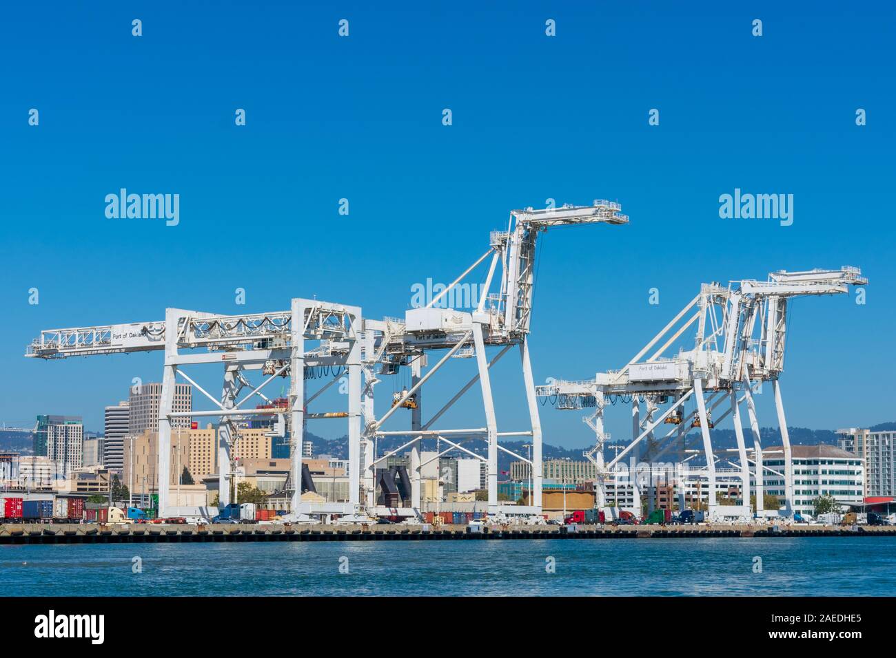 Anzeigen von Oakland International Container Terminal und Oakland Downtown aus dem Wasser auf den Hafen Kanal. Container Cargo Kran steht neben Conta Stockfoto