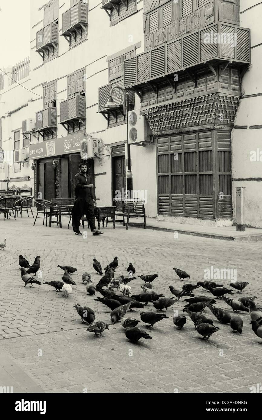 Arabisch Mann vorbei gehen. Eine Herde von Tauben sitzen auf der Straße in der Altstadt von Al Balad, Jeddah, KSA, Saudi-Arabien Stockfoto