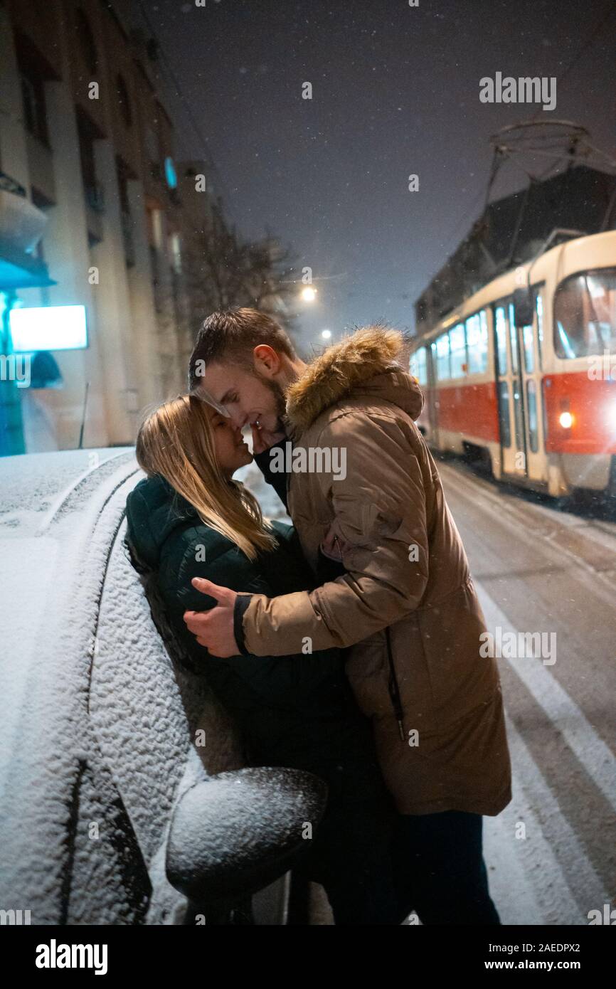 Junge erwachsene Paare küssen einander auf schneebedeckter Straße Stockfoto