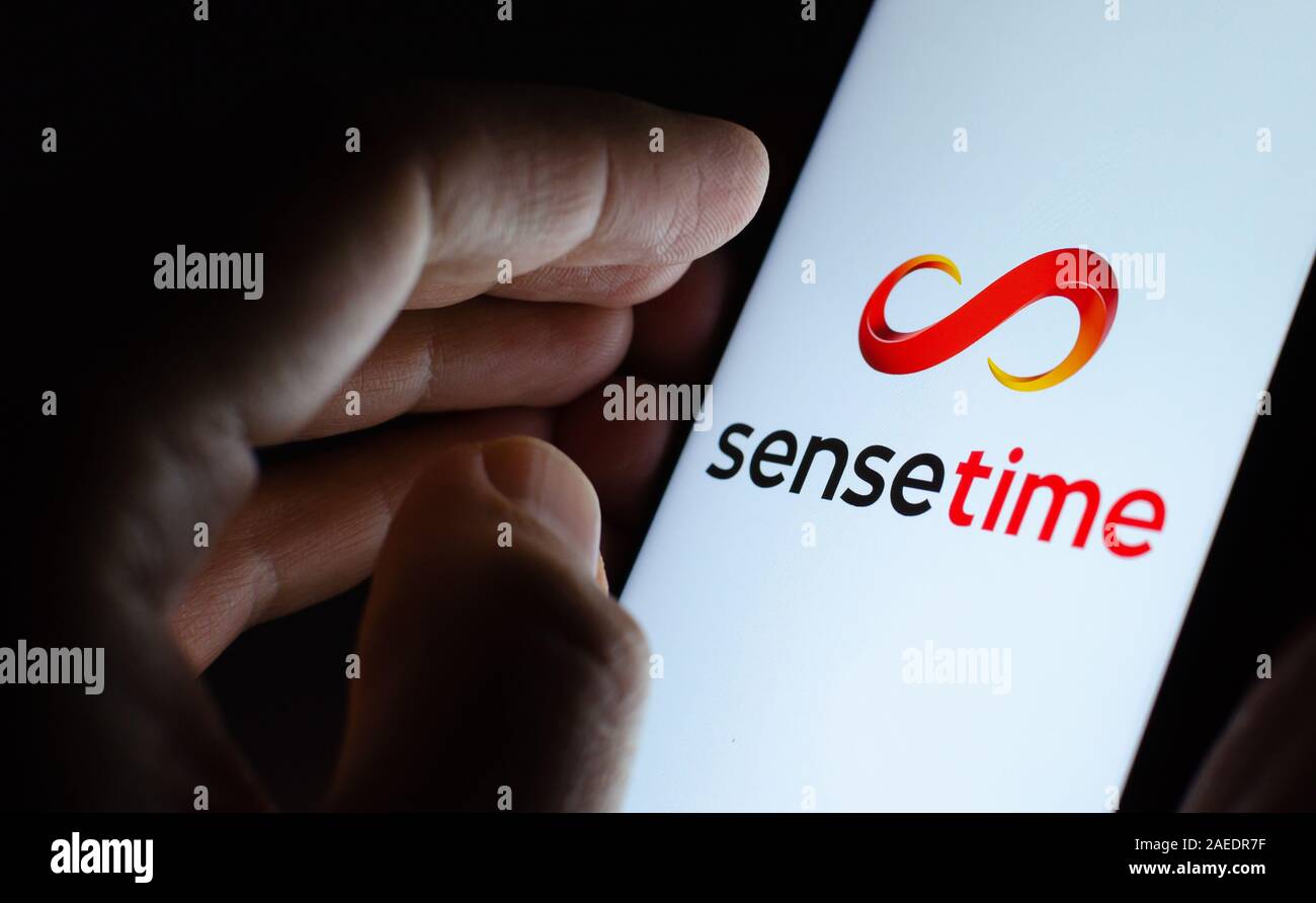 SenseTime Logo auf einem leuchtenden Bildschirm und eine Hand auf ihn gerichtet. Stockfoto