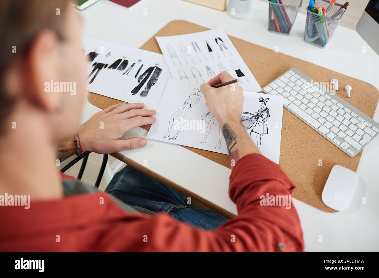 Hohe Betrachtungswinkel bei tätowierten Mann Mode Designer Skizzen am Arbeitsplatz im Studio oder Atelier, kopieren Raum Stockfoto