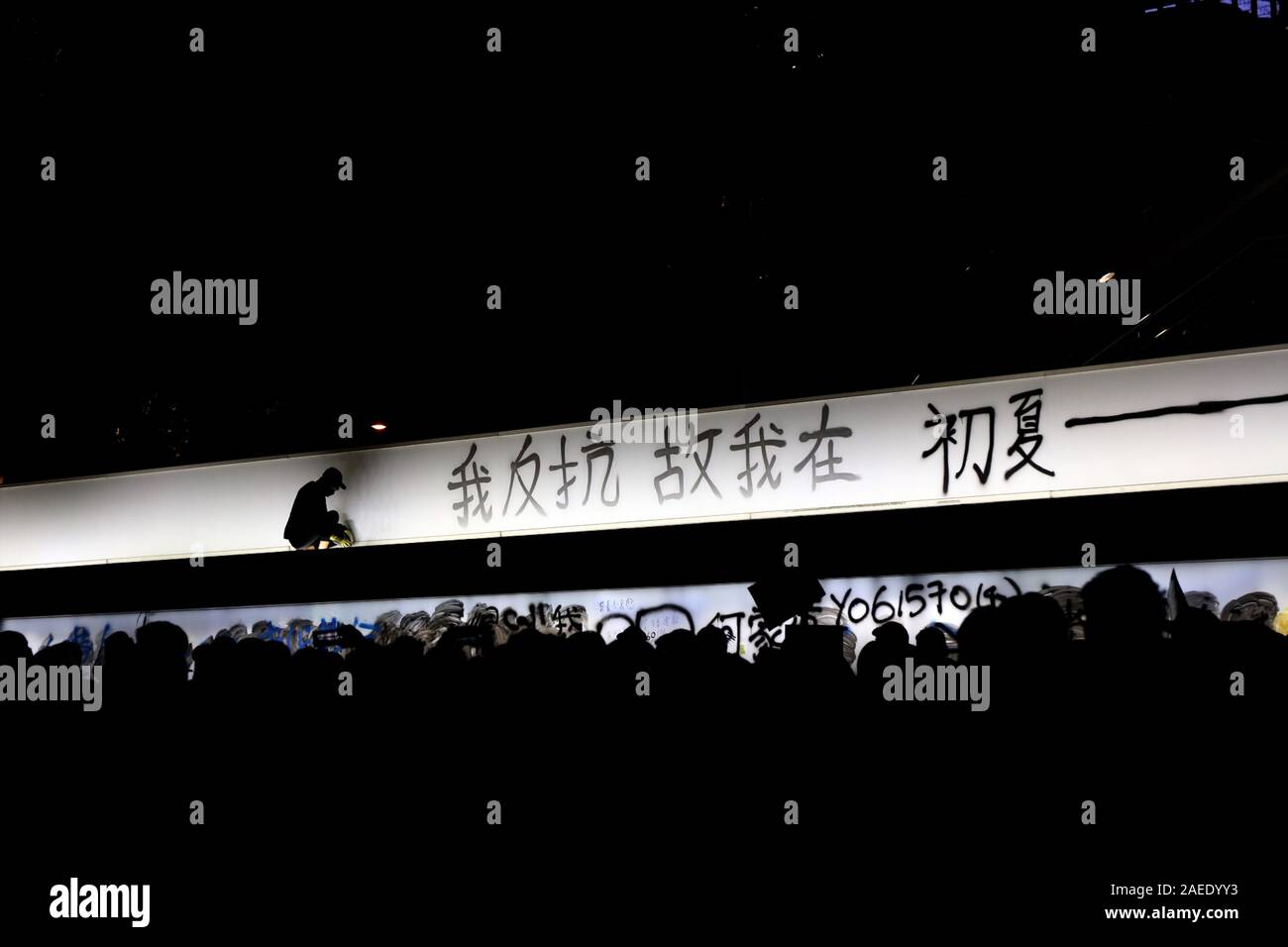 Eine schwarz gekleidete Demonstrant sprühen Farben die Worte "Ich widerstehen, also bin ich' auf einer Straßenbahn-Station als eine Masse von unten aussieht. Stockfoto