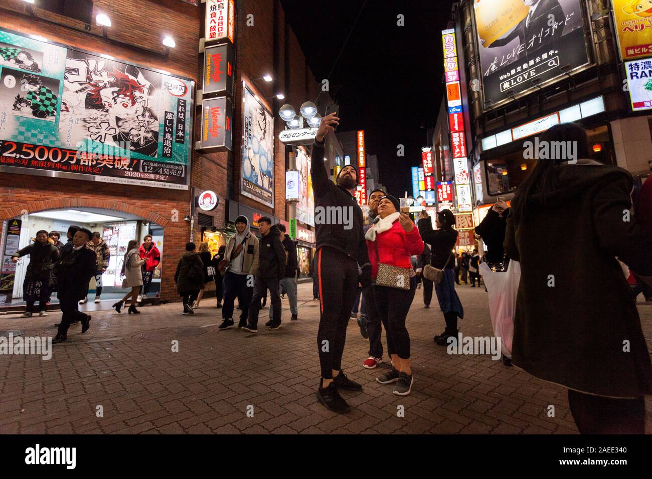Eine Gruppe asiatischer Touristen nimmt Selfies im Centre Gai Shibuya, Tokio, Japan, auf. Stockfoto