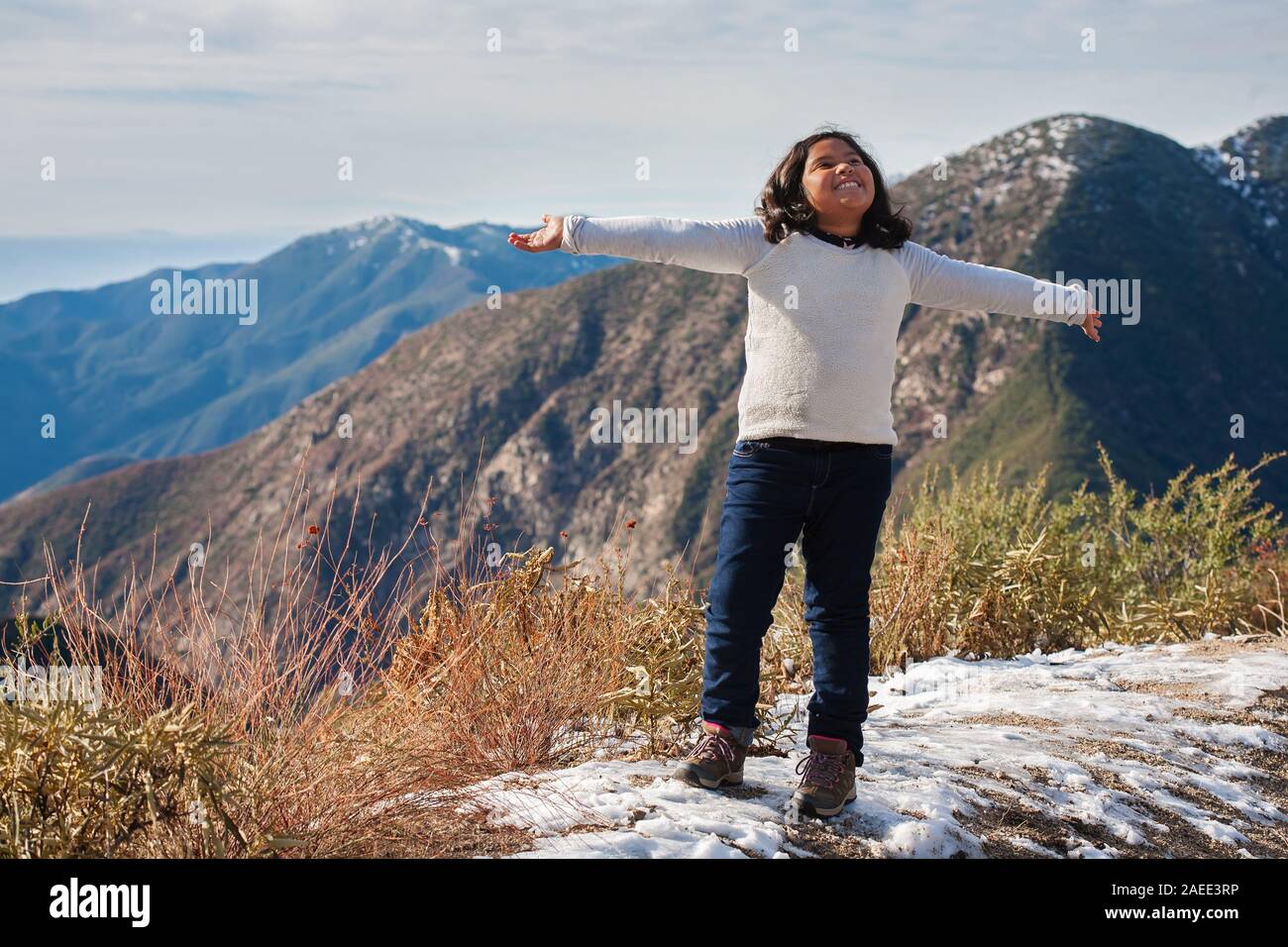 Ein kleines Mädchen am Rande eines schneebedeckten Berg, Freude ausdrücken nach Erreichen der Wanderwege Gipfel in San Bernardino Berge. Stockfoto