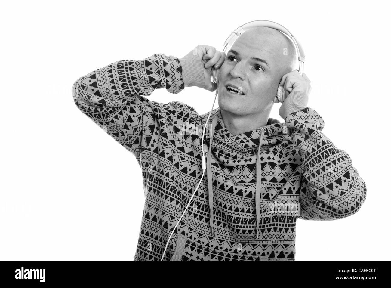 Studio shot der Jungen glücklich glatzköpfige Mann lächelnd, während Sie Musik hören und denken Stockfoto