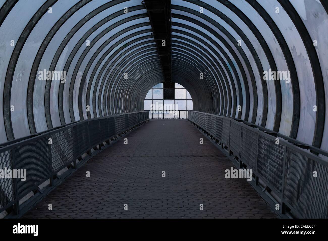 Einen langen Fußgängertunnel mit Metall und Glas Design. Antenne Fußgängerüberweg über die Autobahn, die Perspektive auf den Horizont geht, eine dunkle zuvorzukommen. Stockfoto