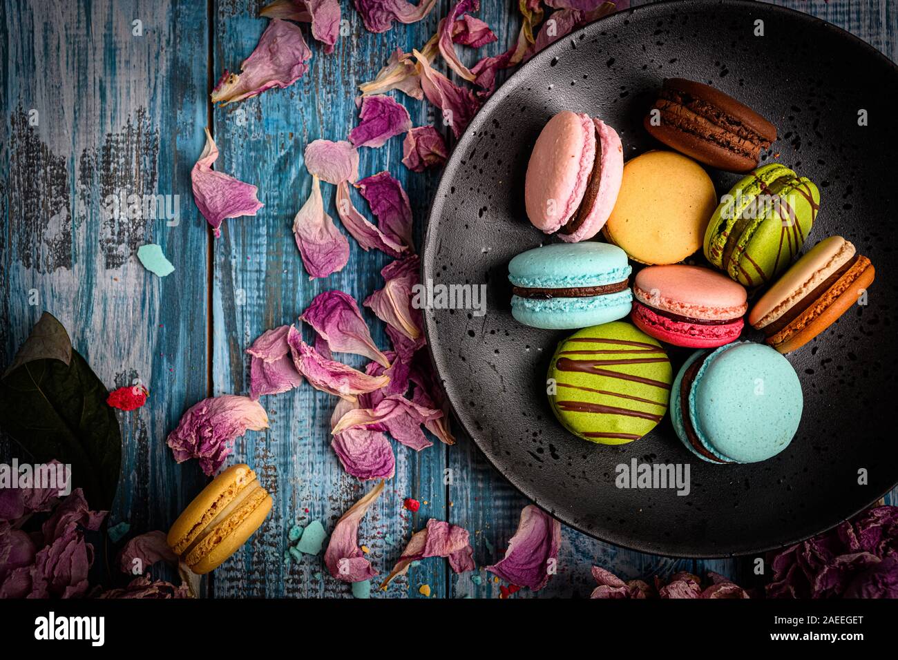 Tolles Foto der sortierten und bunte Makronen arrangiert Schön oben auf Blau Holztisch mit lila Blüten dekoriert Stockfoto
