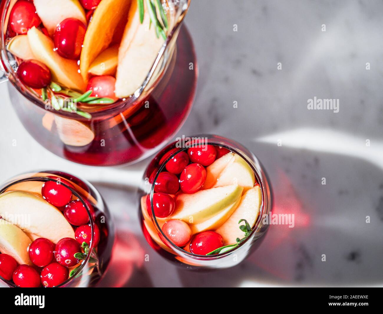 Winter Sangria auf der Tischplatte mit grau Leinen Tischdecke. Gläser Sangria mit Obst schneiden, Cranberry und Rosmarin. Kopieren Sie Platz für Text oder Design. Top View oder flach. Horizontale. Stockfoto