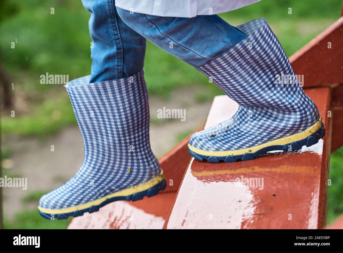 Junge in blau Gummistiefel hinunter die nassen rutschigen Treppen in den regnerischen Tag. Kind Sicherheitskonzept Stockfoto