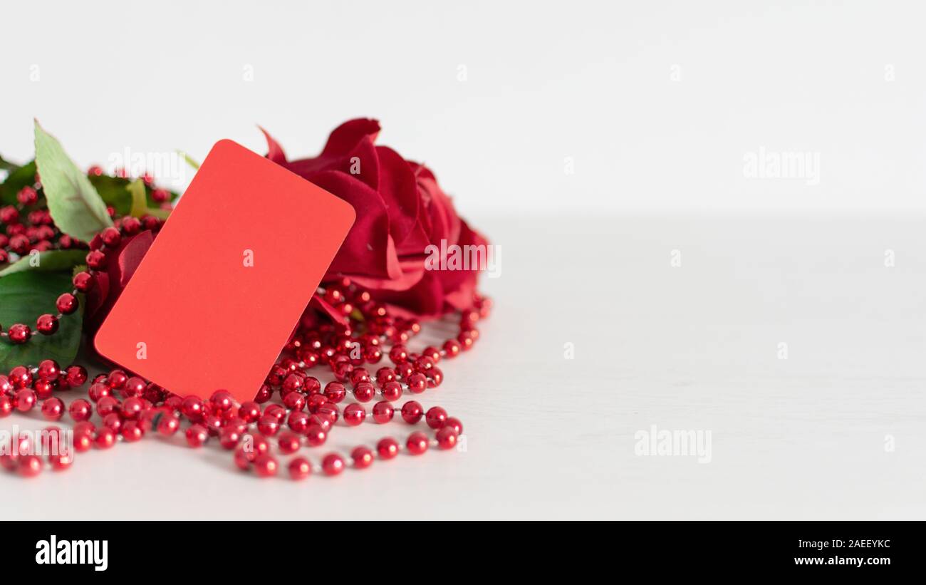 Valentines oder Jahrestag Geschenk und ein paar schöne rote Rosen mit einer angehängten Rot leer Geschenkanhänger für ihre Grüße oder Nachricht. Kopieren Sie Platz. Stockfoto