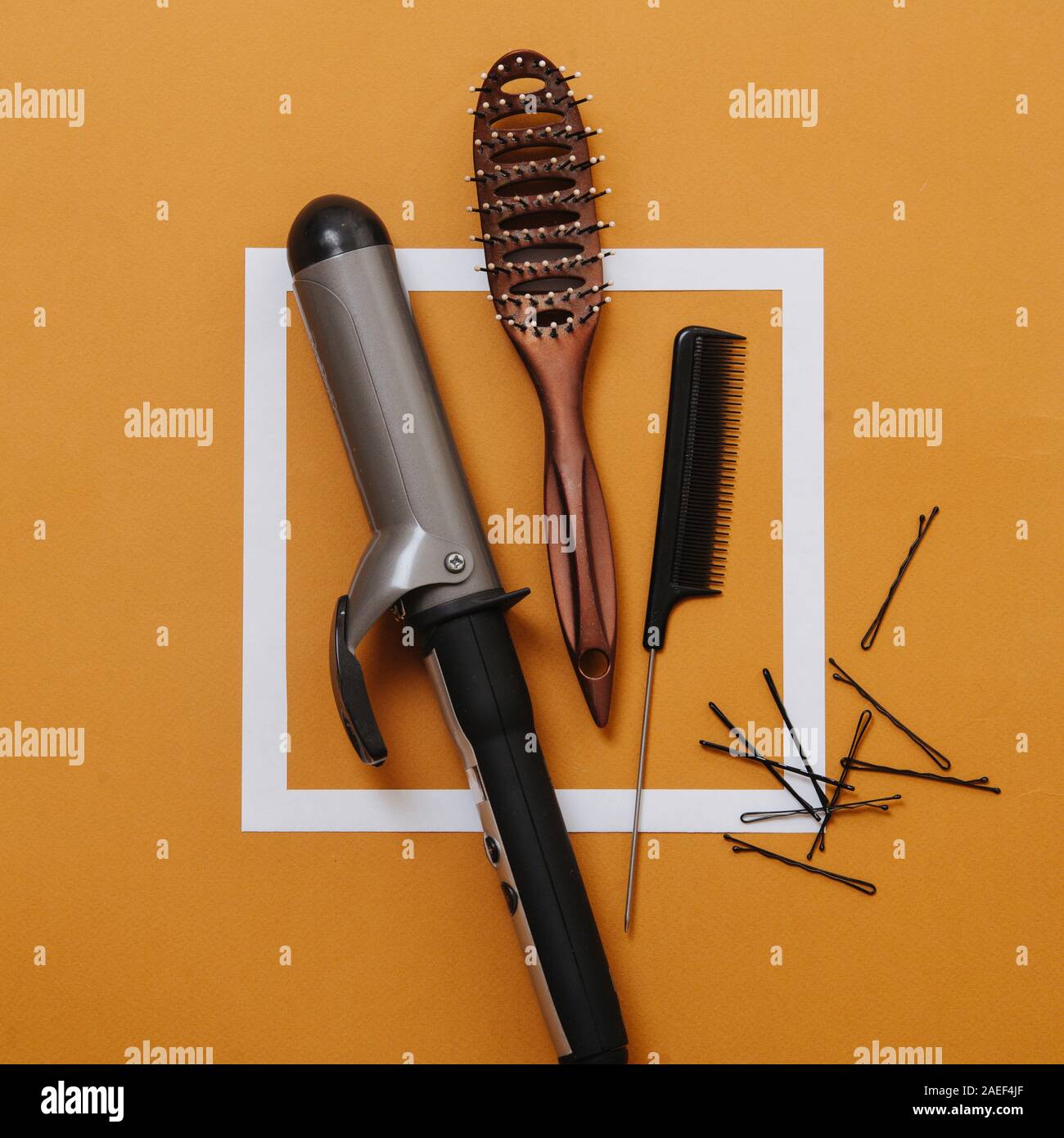 Friseur- tools: Lockenstab, Haarbürste, rattenschwanz Kamm, bobby Pins über Orange Stockfoto