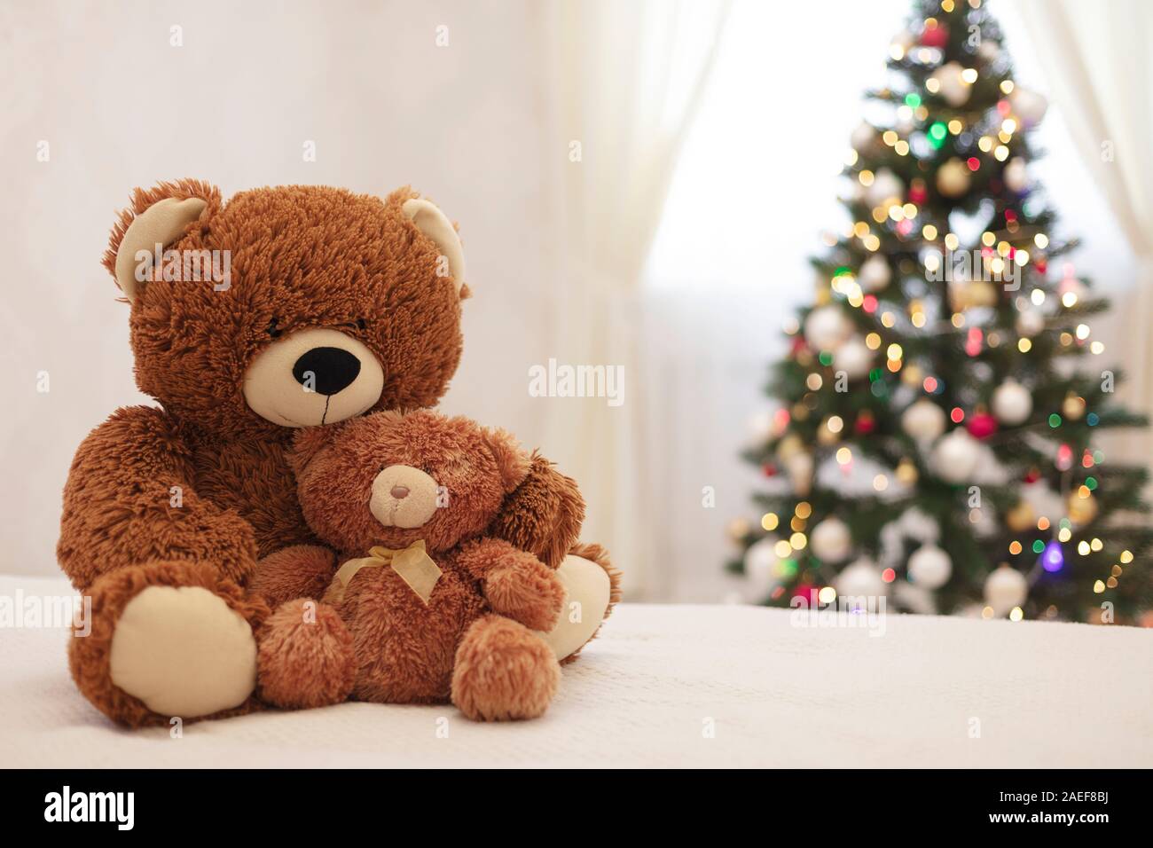 Frohe Weihnachten! Kinder Spielzeug Teddybären Große und Kleine sitzen auf dem Sofa vor dem Hintergrund der Weihnachtsbaum. Selektive konzentrieren. Stockfoto