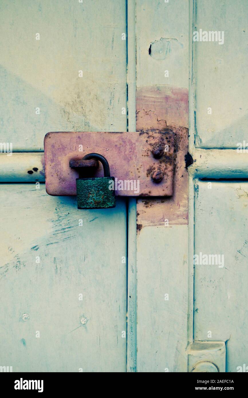 Rostiger Vorhängeschloss und beschädigte Metalltür Stockfoto