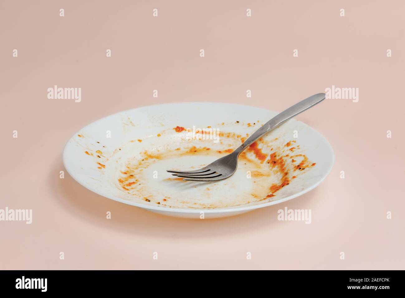 Ein Teller mit Resten von Tomatensauce. Ungewaschen Gerichte illusatration, schmutzige Teller auf hellen Hintergrund Stockfoto