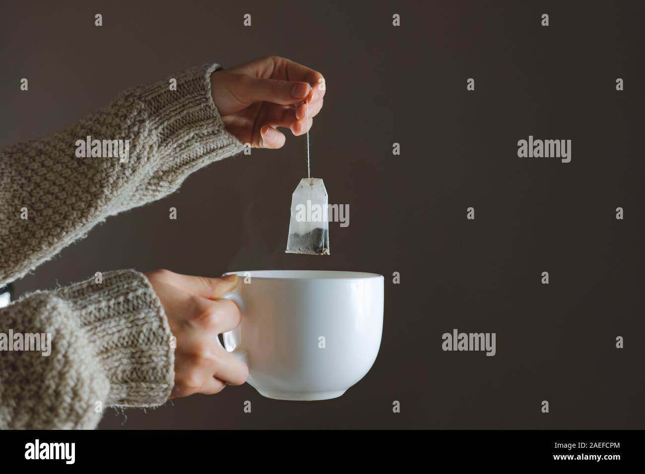 Tee in der kalten Jahreszeit zuhause. Nahaufnahme von. Eine Person in gemütlichen Pullover, Kräuter- oder Heilung Tee, Idee der Home Heilung aus kalt Stockfoto