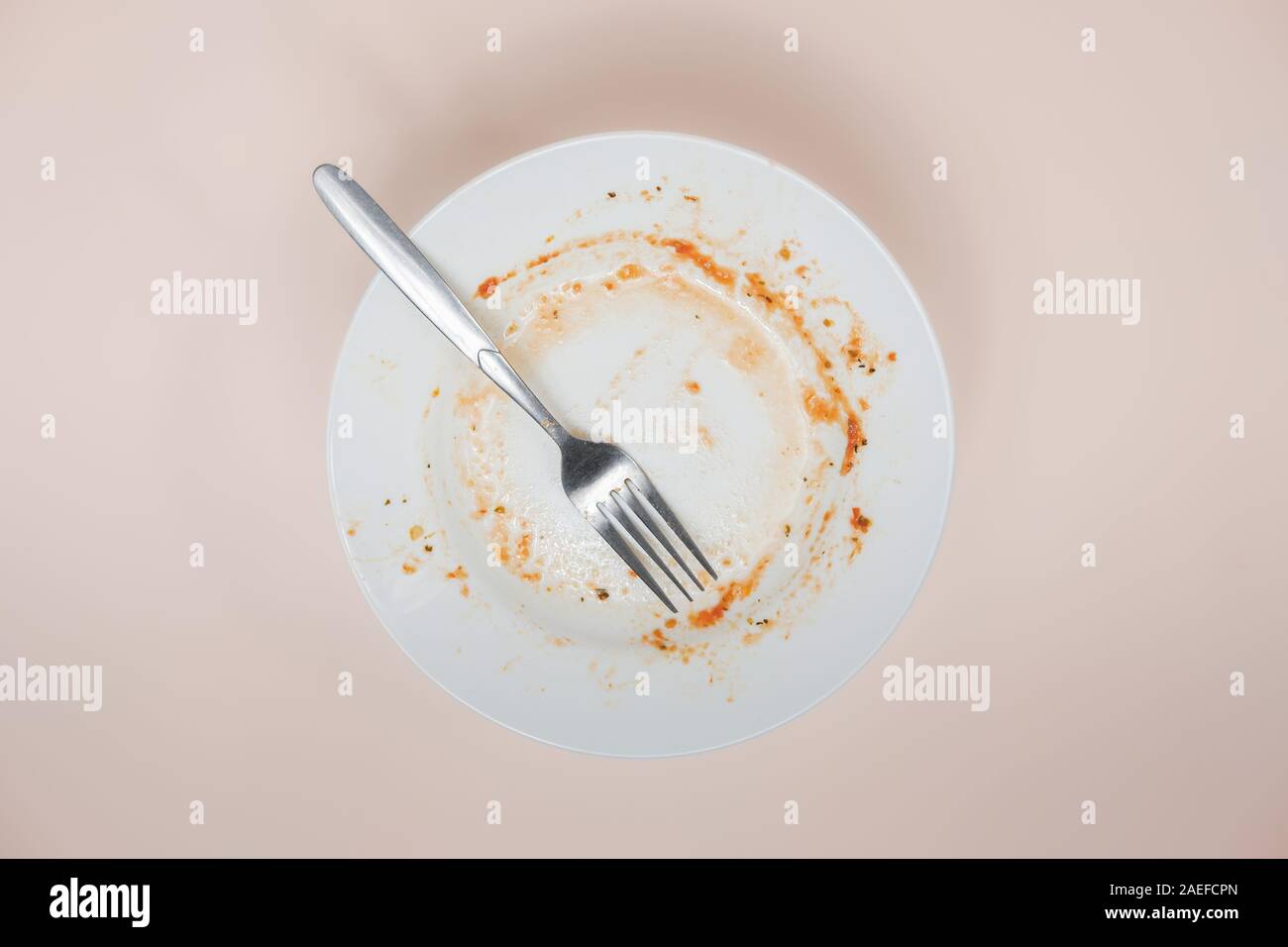 Ein Teller mit Resten von Tomatensauce, Ansicht von oben. Ungewaschen Gerichte illusatration, schmutzige Teller auf hellen Hintergrund Stockfoto