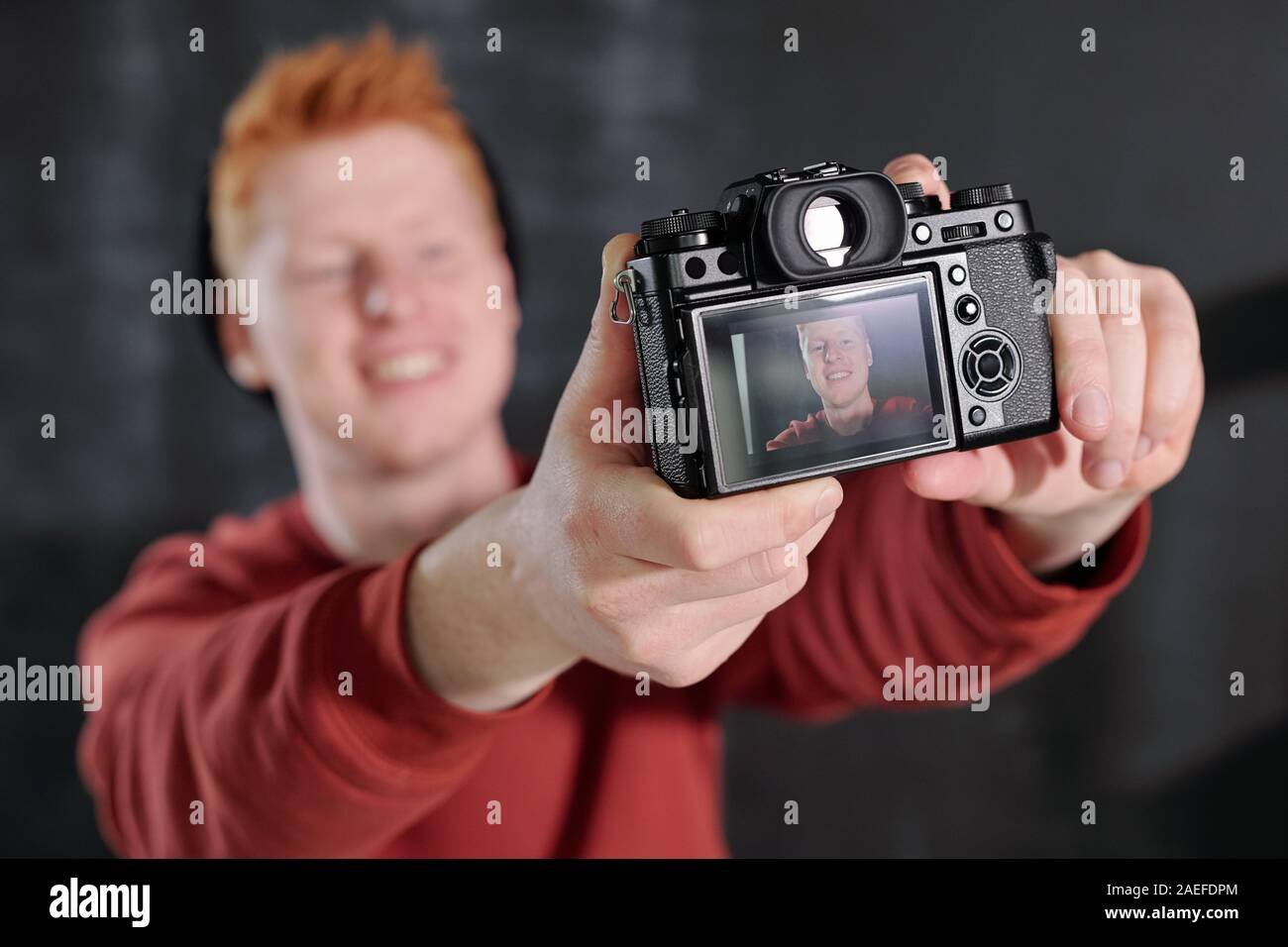 Hände von fröhlicher junger vlogger Holding Kamera vor sich selbst im Studio Stockfoto
