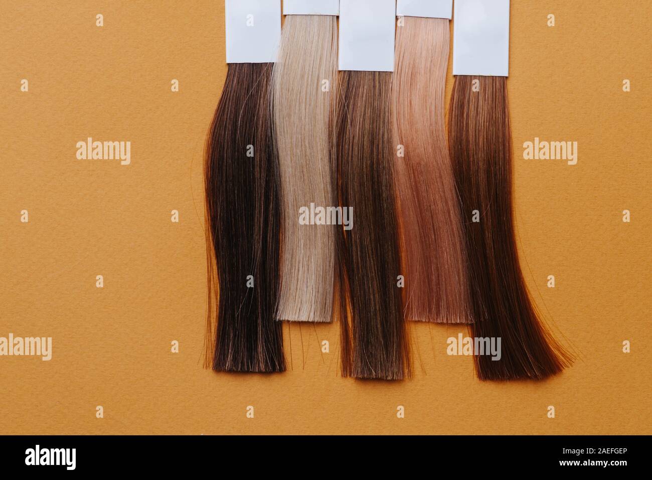 Vertikale Reihe von gefärbtem Haar Schlösser. Proben in Friseursalon auf orange Oberfläche Stockfoto