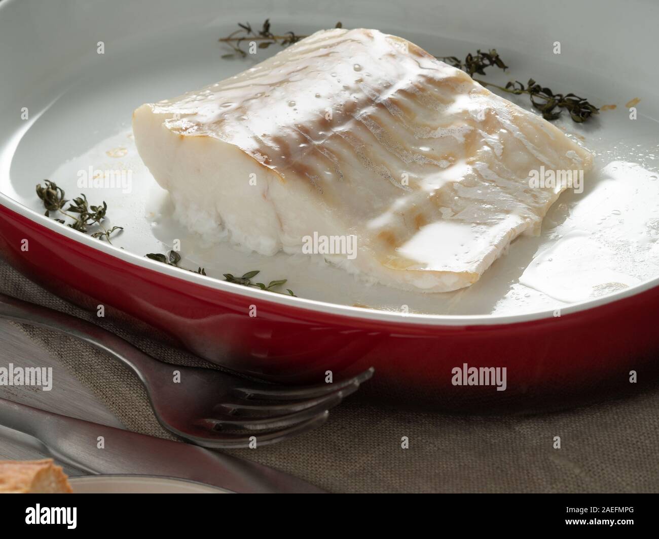 Kabeljau Fisch Filet, frisch im Backofen gekocht mit Thymian in einer porzellanschale zum Backen, Nahaufnahme, Seitenansicht Stockfoto