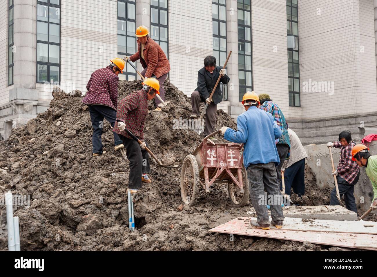 Weibliche WanderarbeiterInnen Schaufeln Erde auf Baustelle, Shanghai, China Stockfoto