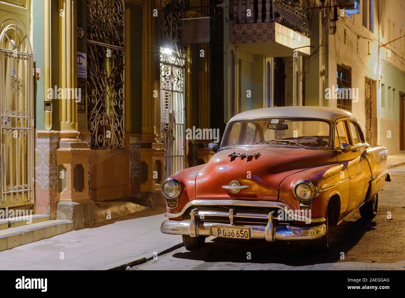 Eine abendliche Straßenszene in Havanna, Kuba mit einem klassischen Amerikanischen Auto unter Straßenlaterne. Als ein eigenes Auto benutzt, da es kein Taxi Aufkleber auf dem Bildschirm. Stockfoto