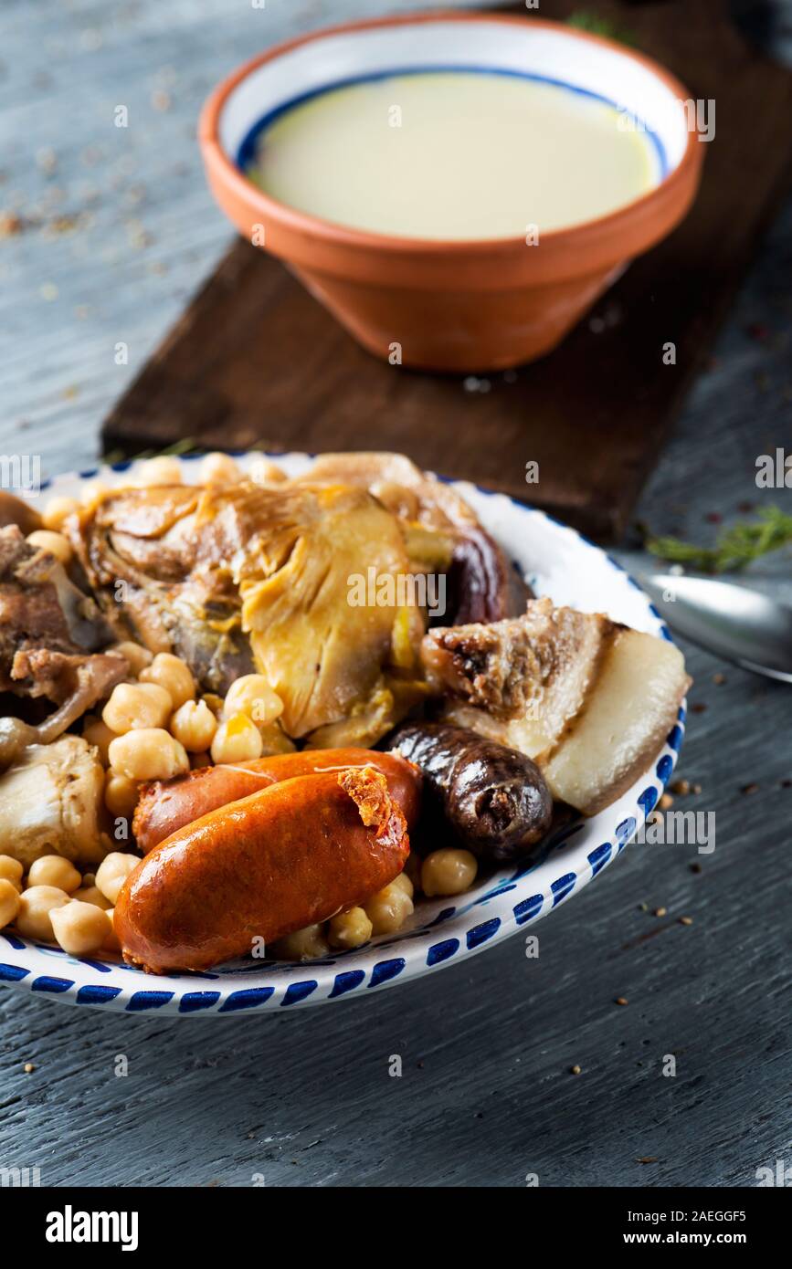 Cocido madrileno, typisch für Madrid, Spanien, mit der Suppe in einem irdenen Schüssel geben und das Fleisch und Gemüse in der Brühe verwendet serviert serviert in einem Fach Stockfoto