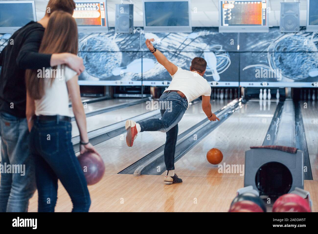 Tun Sie es mit Licht Stärke. Junge fröhliche Freunde viel Spaß beim Bowling Club an den Wochenenden Stockfoto