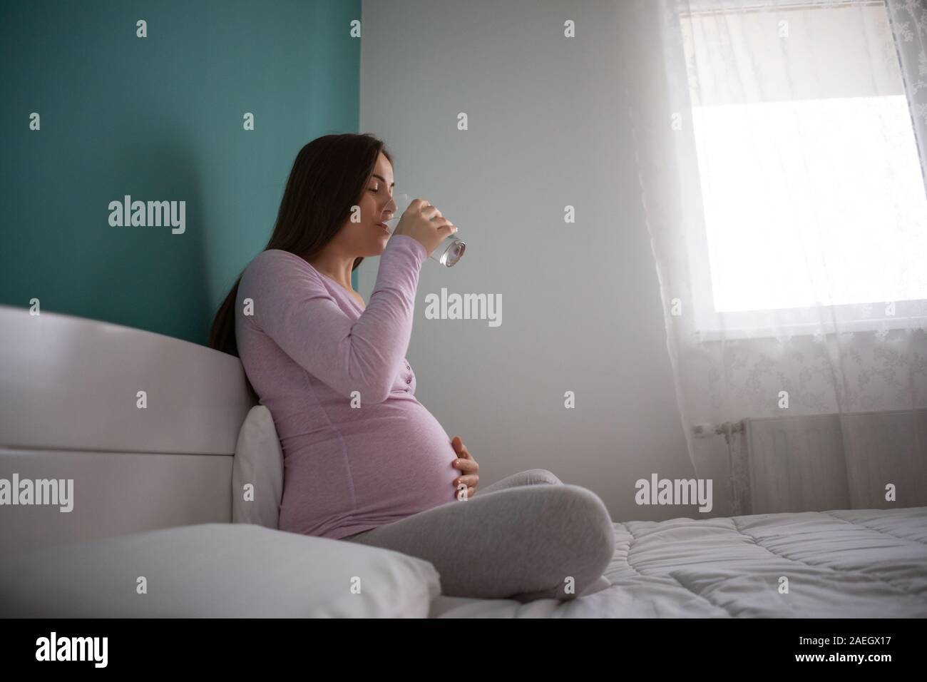 Glücklich schwanger Frau trinkt Wasser und entspannt zu Hause. Stockfoto