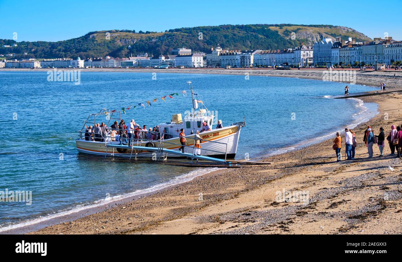 Besucher weg whiile Sea-Jay tour Boot, andere warten an Bord, am Strand in Llandudno, Wales Hafen Stockfoto