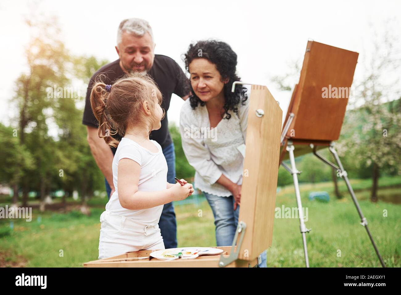 Sie tun es gut. Großmutter und Großvater haben Spaß im Freien mit Enkelin. Malerei Konzeption Stockfoto