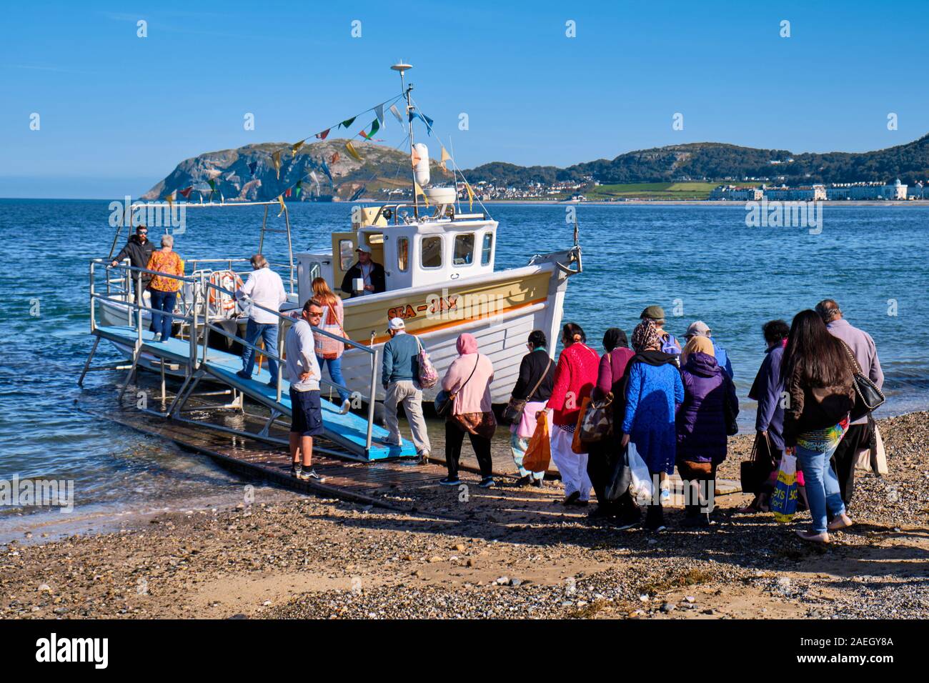 Besucher getting off Tour Boot, whiile andere warten an Bord, am Strand in Llandudno, Wales Hafen Stockfoto