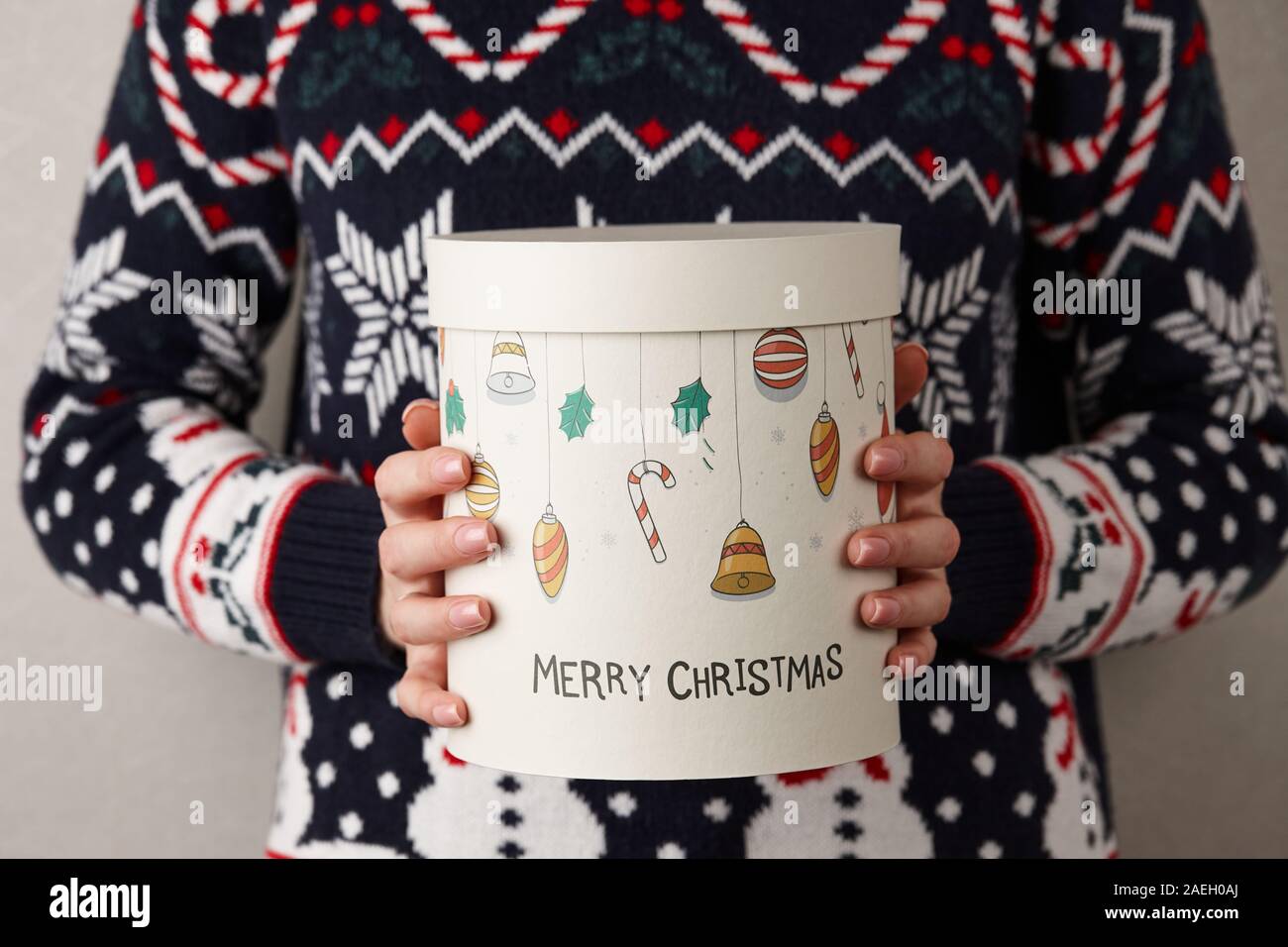 Frau in Urlaub Pullover mit Weihnachten Geschenk Box auf grauen Hintergrund, Ansicht schließen Stockfoto