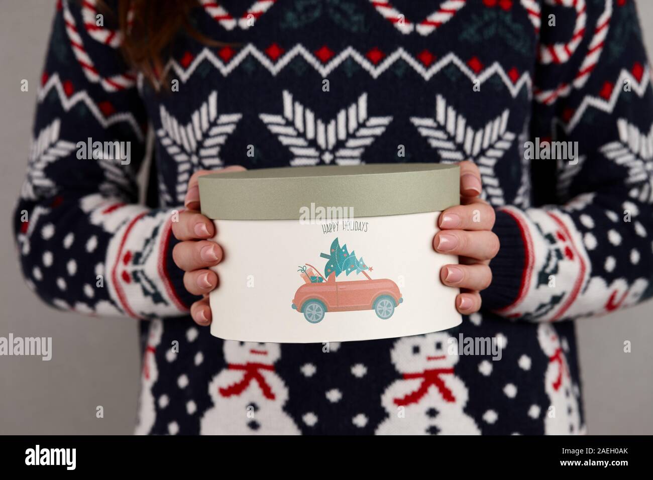 Frau in Urlaub Pullover mit Weihnachten Geschenk Box auf grauen Hintergrund, Ansicht schließen Stockfoto