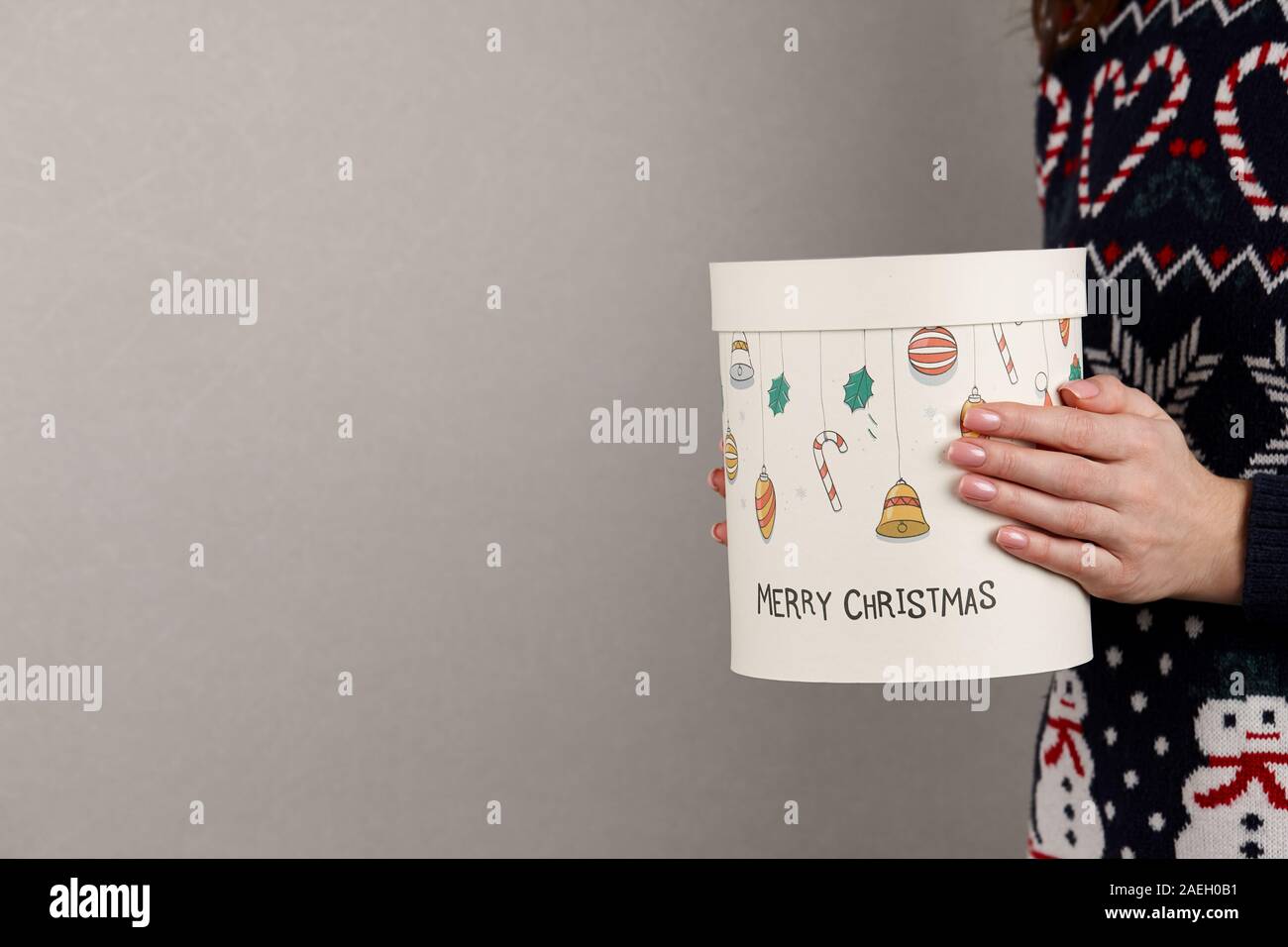 Frau in Urlaub Pullover mit Weihnachten Geschenk Box auf grauen Hintergrund, Ansicht schließen Stockfoto